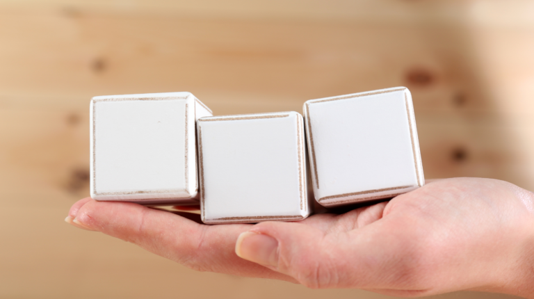 This is an image of a hand holding three white blocks.